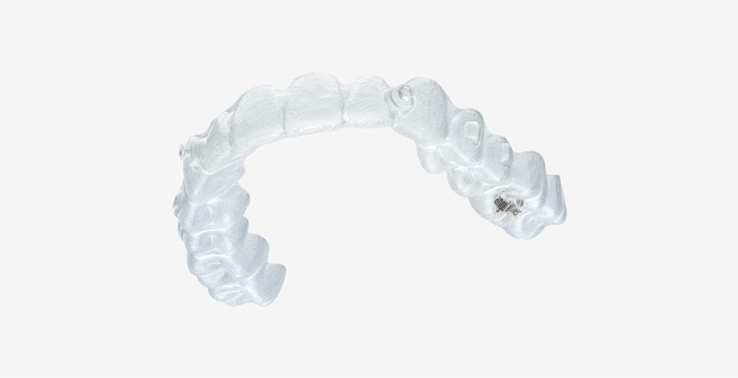 A clear, curved dental aligner is shown on a plain white background, designed to fit over teeth for orthodontic adjustment.