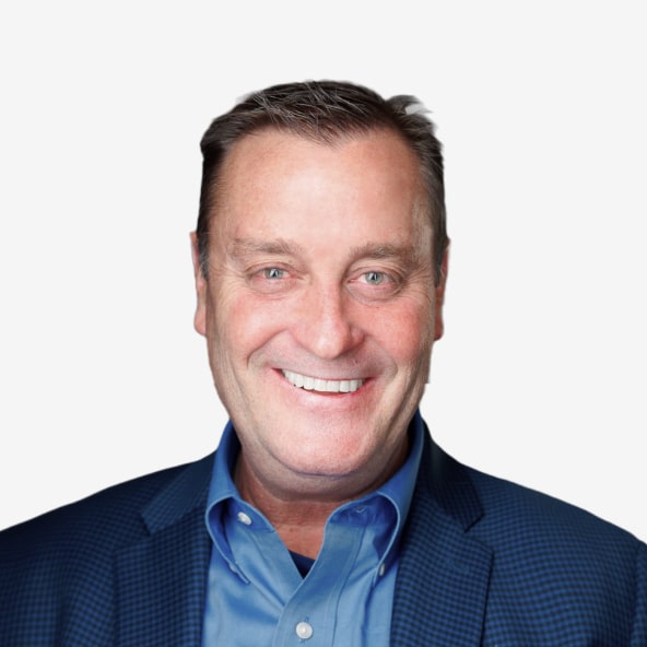 A middle-aged man with short brown hair smiles at the camera. He is wearing a blue dress shirt and a blue patterned blazer, posed against a plain white background.