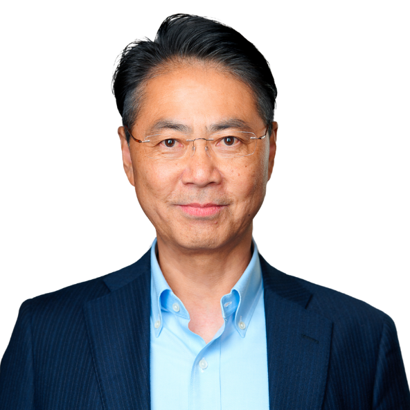 Koichi team page A middle-aged man with short black hair and glasses wears a blue collared shirt and a dark pinstripe jacket, smiling gently against a plain white background.